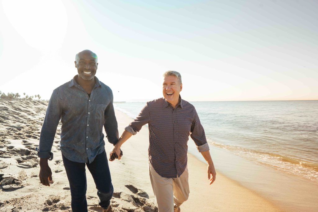 Mixed race elder gay couple on beach